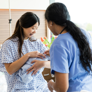 Postnatal mother holding baby with nurse support at home
